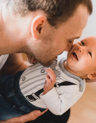 Portrét šťastného otecka so svojim bábätkom počas rodinného fotenia doma od profesionálneho fotografa