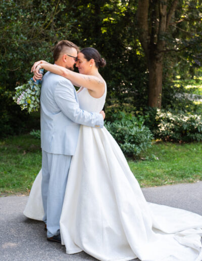 Nevesta a ženích sa držia za ruky počas západu slnka, usmievajú sa a stoja na lúke so zlatým svetlom v pozadí.