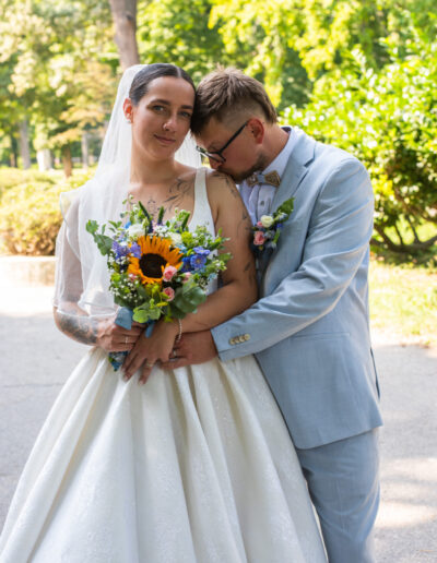 nevesta a ženích objímajúci sa pod stromami, prirodzená svadobná fotografia v jemnom svetle.