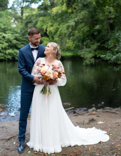 nevesta a ženích objímajúci sa pod stromami, prirodzená svadobná fotografia v jemnom svetle.
