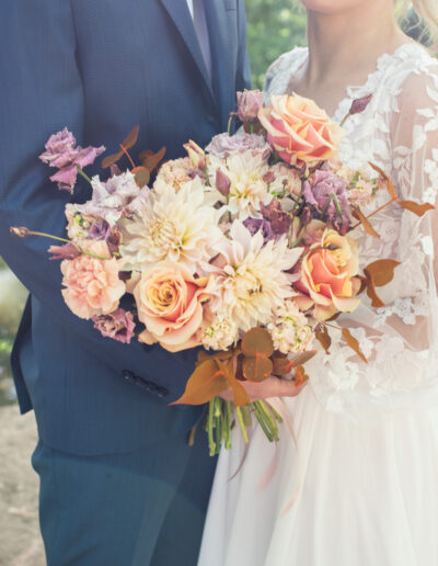 Svadobná fotografia nevesty a ženícha počas západu slnka na lúke, romantický portrét novomanželov v zlatom svetle počas svadobného dňa.