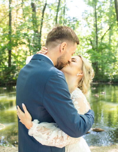 Svadobná fotografia nevesty a ženícha počas západu slnka na lúke, romantický portrét novomanželov v zlatom svetle počas svadobného dňa.