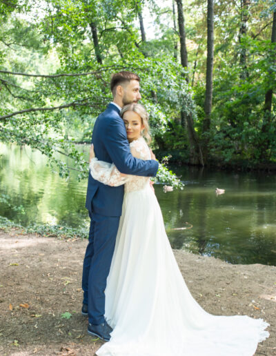 Svadobná fotografia nevesty a ženícha počas západu slnka na lúke, romantický portrét novomanželov v zlatom svetle počas svadobného dňa.